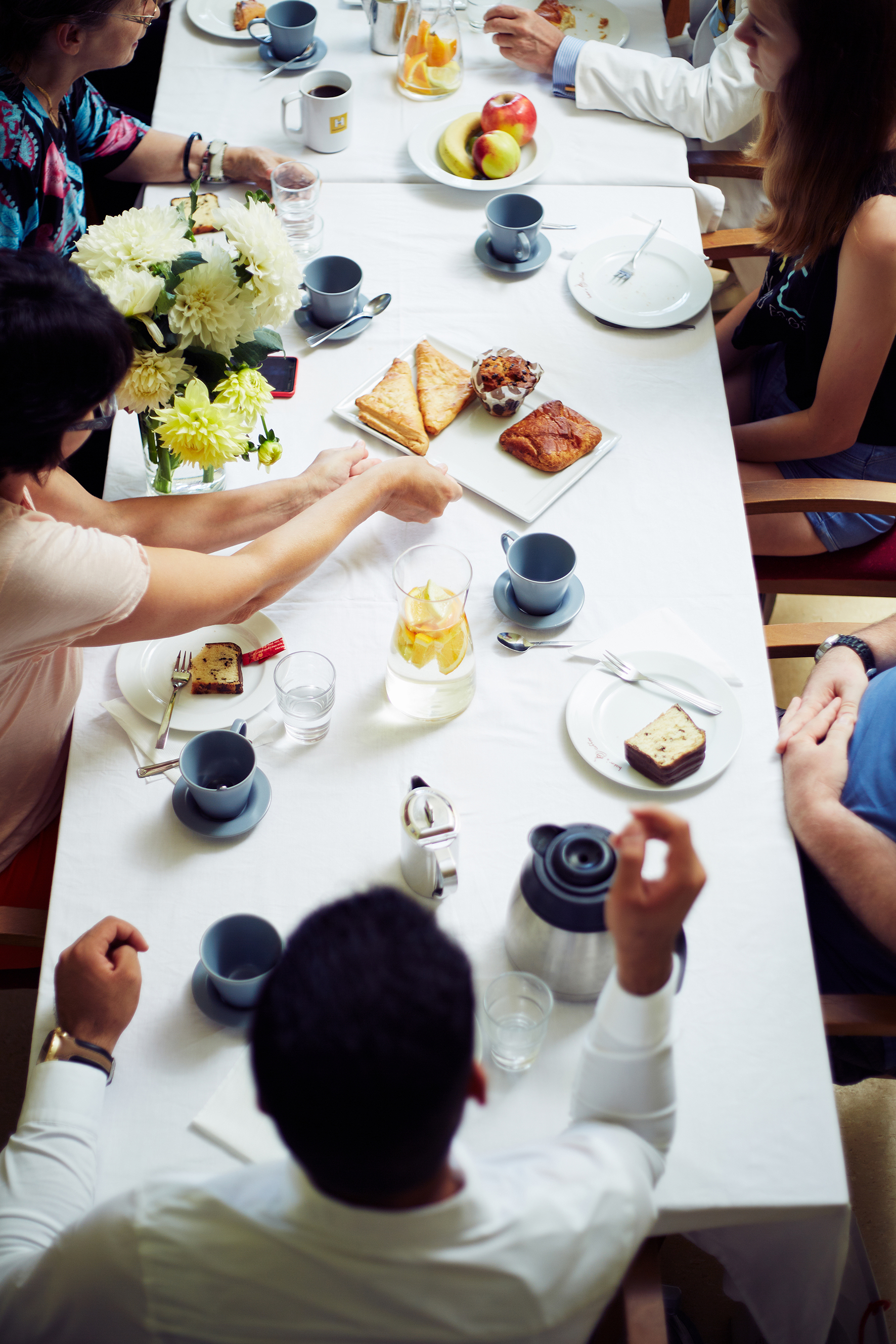 Besucher*innen des Nachbarschaftszentrums frühtücken bei gedecktem Tisch