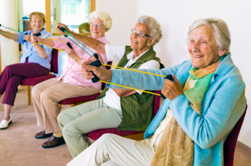Ältere Frauen machen sitzend Übungen mit den Armen.