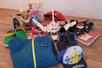 Verschiedene Spielzeuge und Kinderkleidung auf einem Tisch