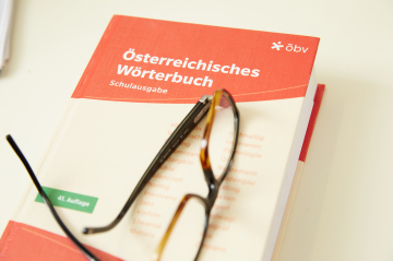 Auf einem österreichischen Wörterbuch liegt eine Brille.