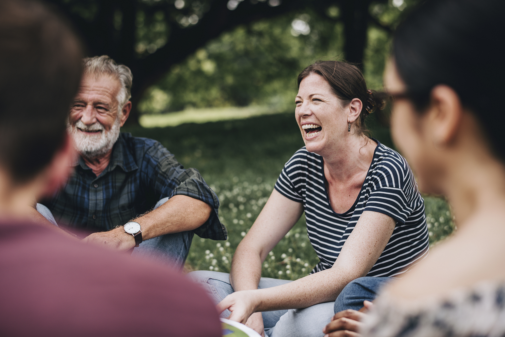 Menschen sitzen auf der Picknickdecke und lachen miteinander