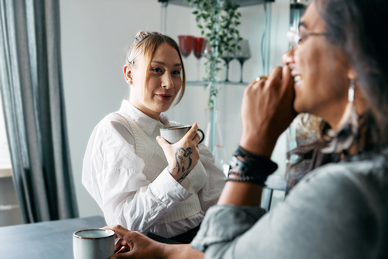 Zwei Frauen mit Kaffeetaschen plauschen miteinander