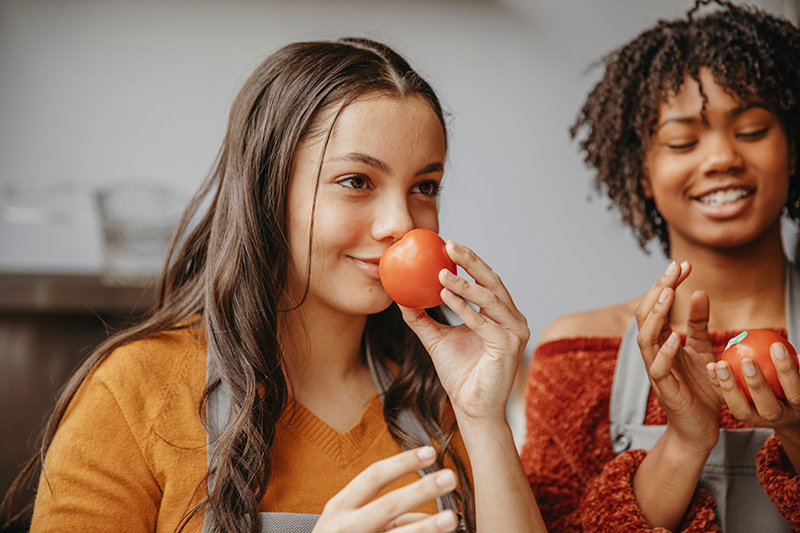 Zwei Freundinnen fühlen und riechen an Obst