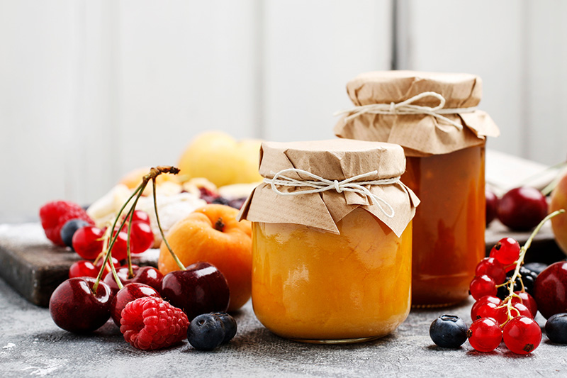 Marmeladegläser mit Obst rundherum.