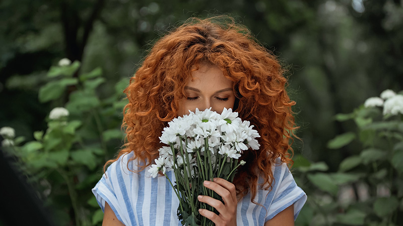 Eine junge Frau riecht an einem weißen Blumenstrauß