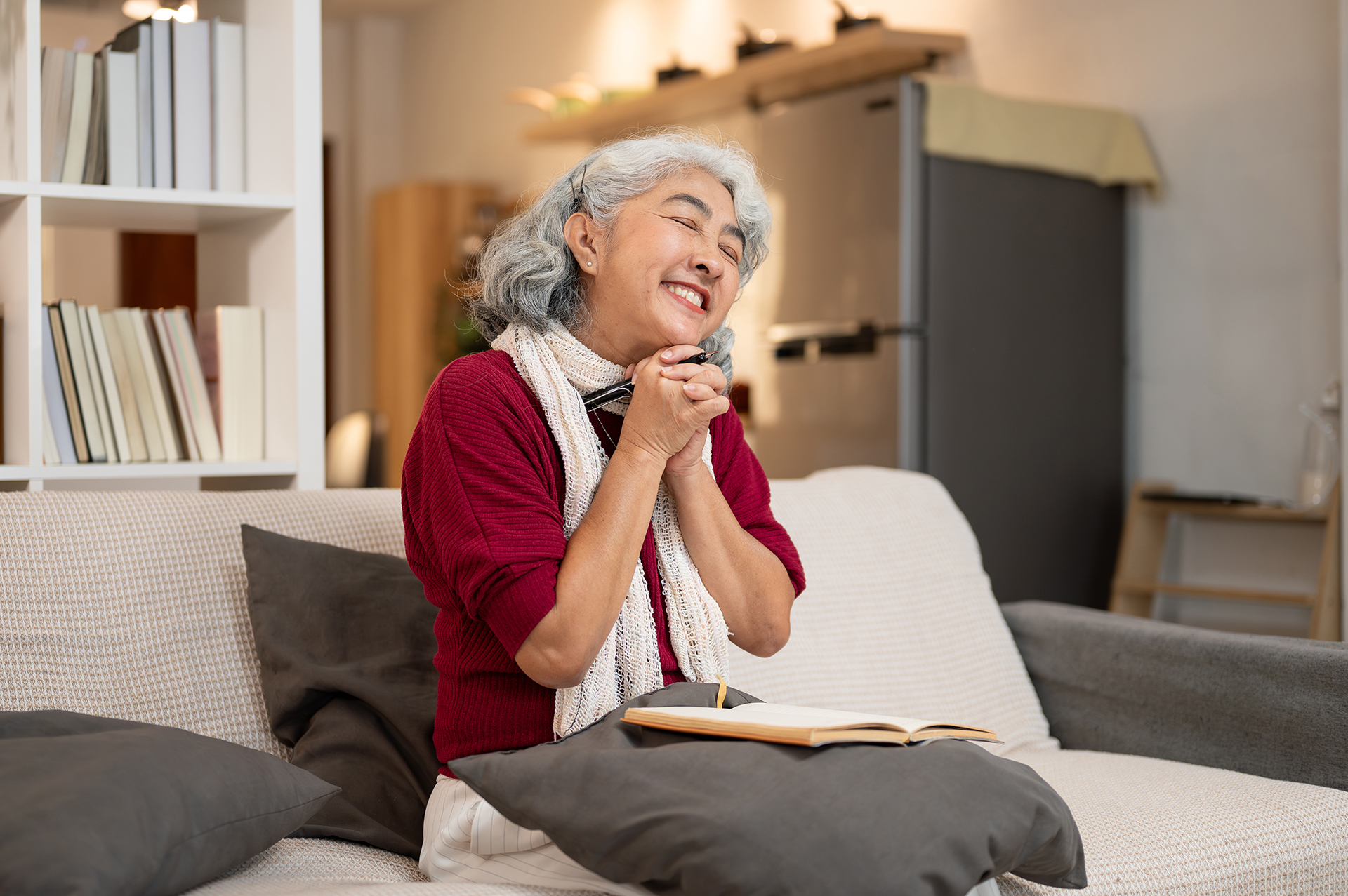 Eine glückliche Frau sitzt auf der Couch mit Stift und Papier