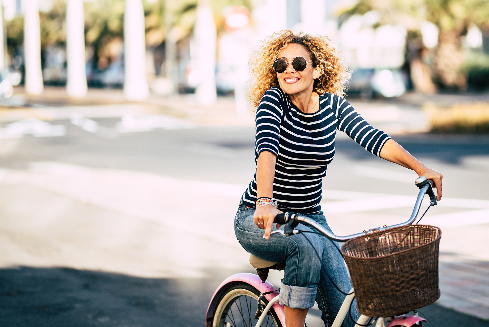 Eine Junge Frau fährt an einem sonnigen Tag fröhlich Fahrrad.