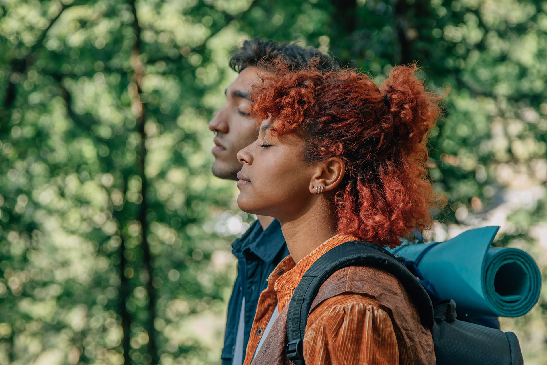 Zwei Menschen stehen im Wald und nehmen die Umgebung wahr.