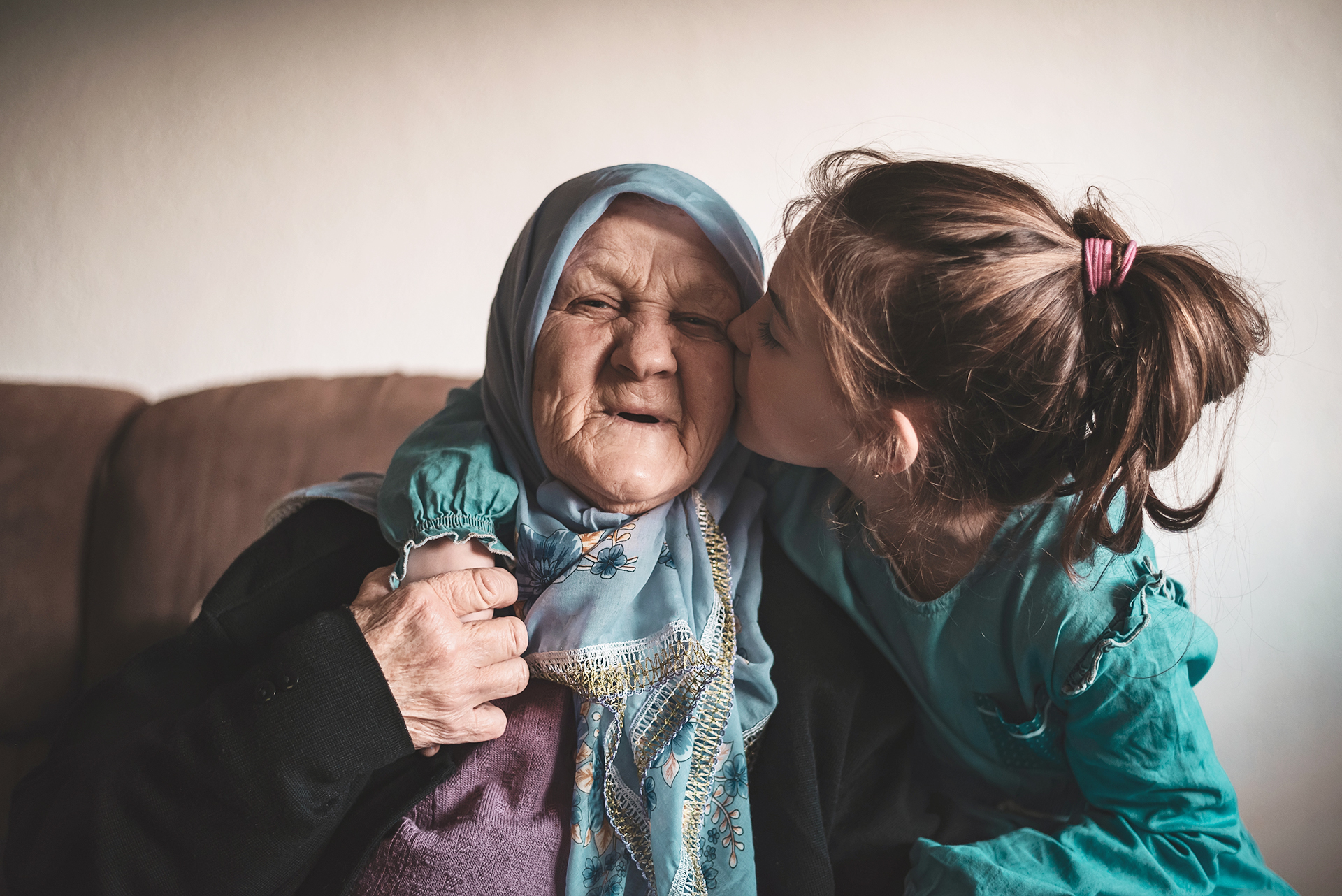 Ein Mädchen gibt ihrer Oma ein Küsschen auf die Wange.