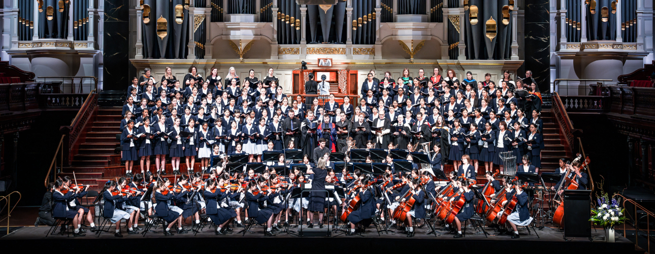 Die Meriden School Sydney spielt in einer Stadthalle ein Konzert: Chorgesang, Bläser, Streicher und Orgel.