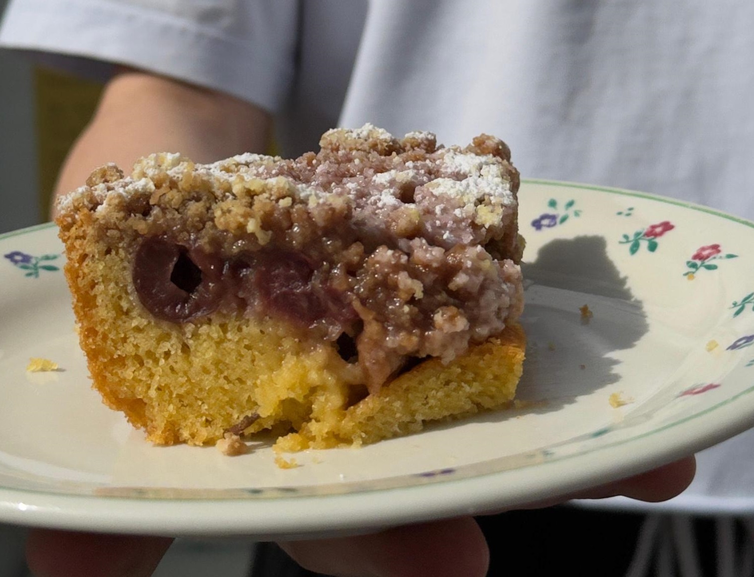 John präsentiert seinen Kirschkuchen vor dem Sprachencafé.