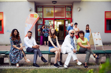 Menschen sitzen vor dem Nachbarschaftszentrum 12