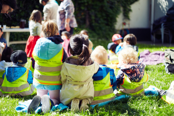 Kinder sitzen auf einer Picknickdecke im Park