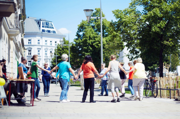 Menschen tanzen im Kreis und halten sich an den Händen im Freien