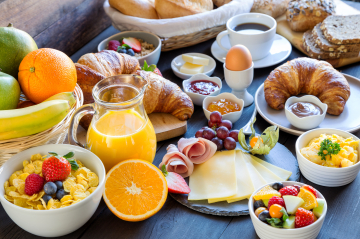 Frühstückstisch mit Obst Gemüse, Saft und Gebäck