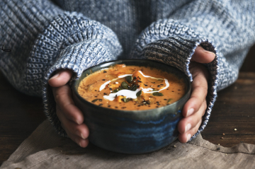 Eine Person hält eine Schale mit Suppe