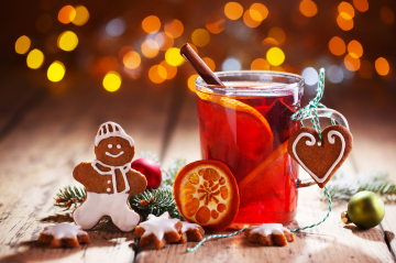 ein schön dekoriertes Glas mit Orangenpunsch, daneben eine lachende Lebkuchenfigur 