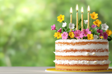 Cupcake mit bunten Geburtstagskerzen, Konfetti und Glitzer.