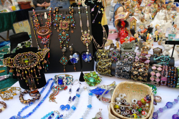 Diverser Schmuck, Armbäder, Ketten etc. werden auf einem Flohmarkttisch angeboten.