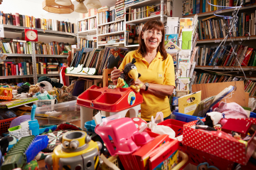 Eine Frau schlichtet Flohmarktsachen im Nachbarschaftszentrum