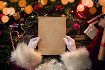 der Nikolaus mit einem Blatt Papier in den Händen, im Hintergrund bunte Adventdekoration