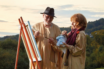 Eine Frau und ein Mann malen ein Portrait in der Landschaft.